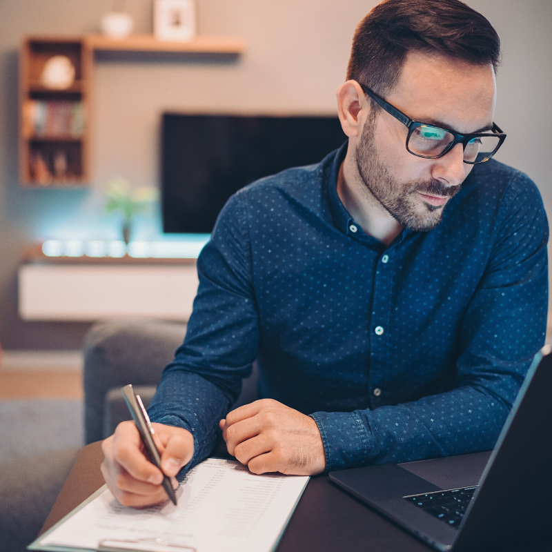 Man in blue shirt  at home sitting in front of his laptop